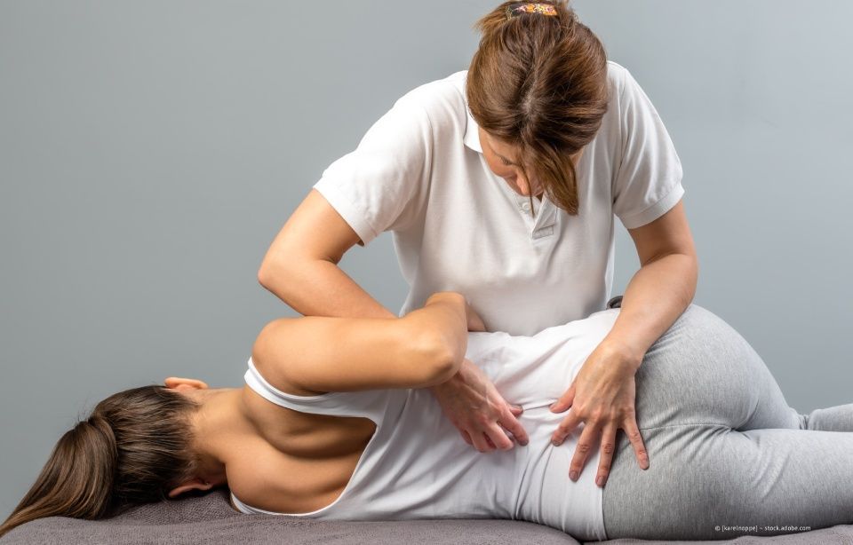 Ein Massagetherapeut massiert den Rücken eines Kunden auf einer grauen Matte in einem Studio.