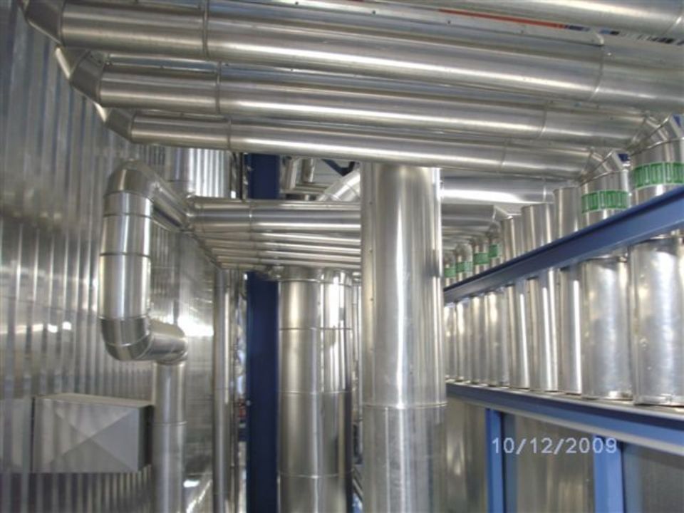 silberne Rohre verlaufen innen an einer Industrieanlage