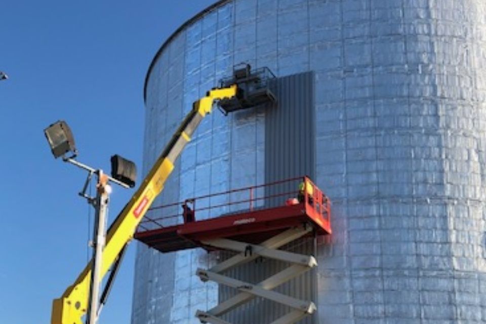 Zwei Hebebühnen an einem silberfarbenen zylinderförmigen Gebäude