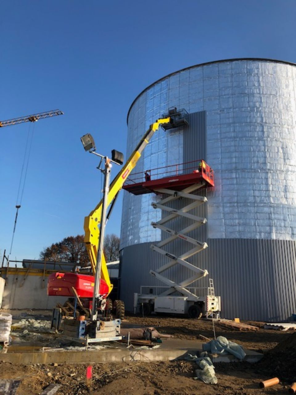 verspiegeltes Gebäude, an dessen Fassade ein Kran Arbeiten verrichtet