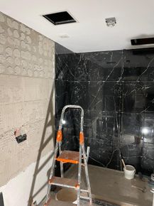 Baño en construcción con paredes de ducha de mármol negro y escalera.