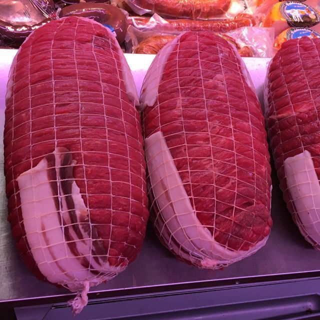 Tres rollos de carne están sobre un mostrador en una carnicería.