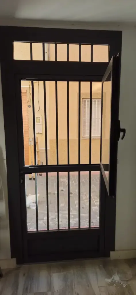 Puerta de seguridad de metal negro con barrotes verticales