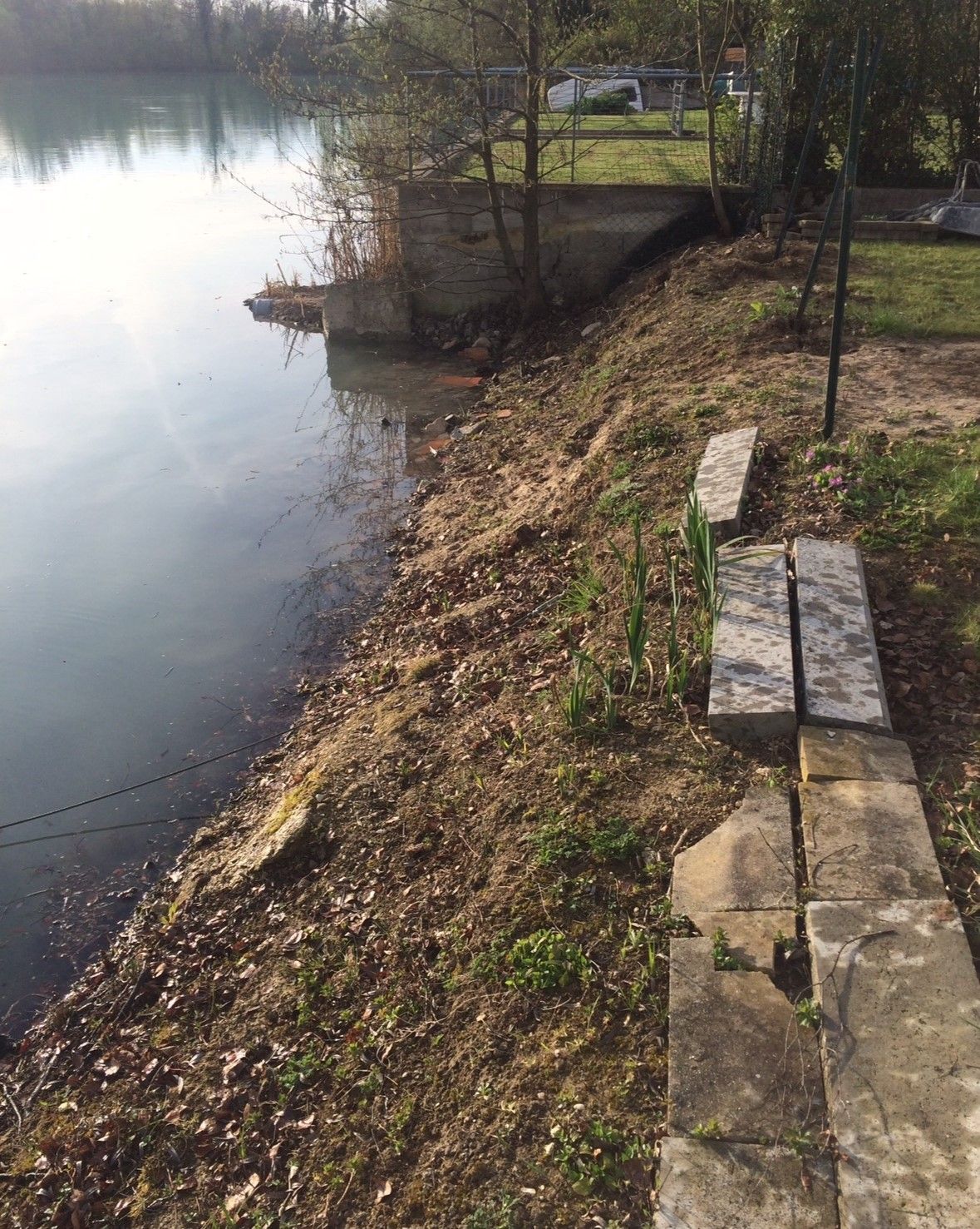 Bordure d'un lac avec bordure en terre et pierre.