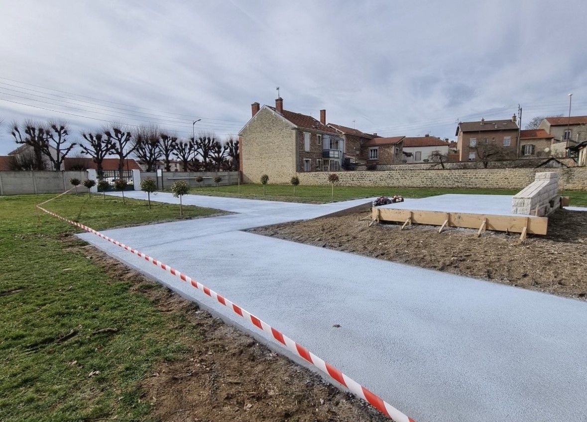 Un chemin de gravier serpente à travers un champ vert, avec un bâtiment en arrière-plan ; construction en cours.