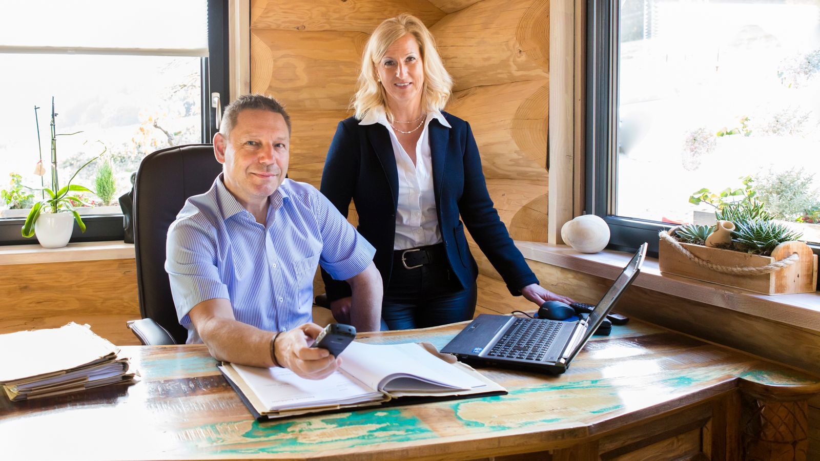 Ein Mann und eine Frau sitzen mit einem Laptop an einem Schreibtisch.