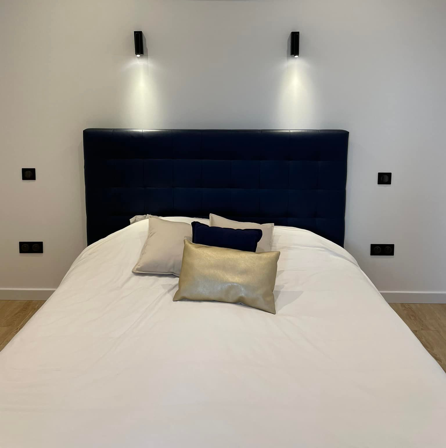 Prises et éclairages dans une chambre vue sur le lit