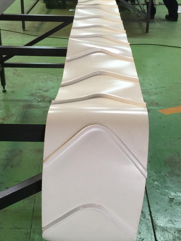 Una cinta transportadora blanca está colocada sobre un suelo verde en una fábrica.