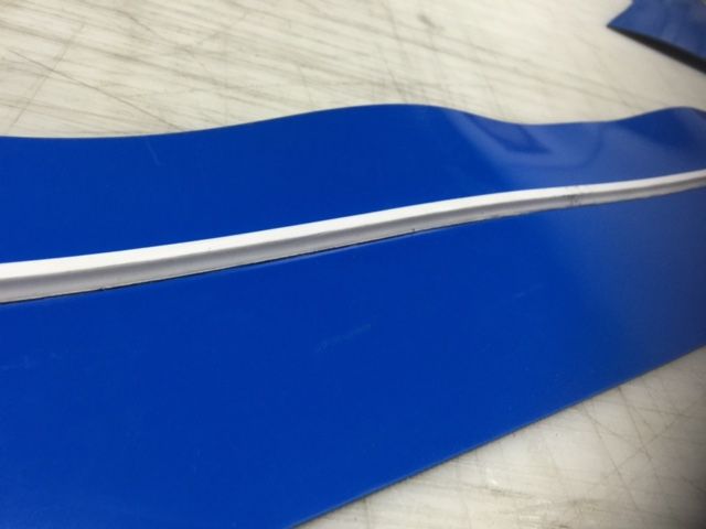 Un trozo de plástico azul con una raya blanca.