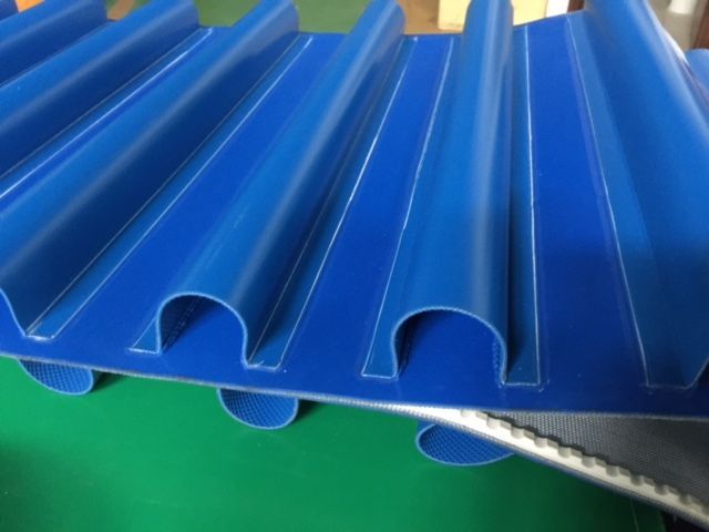 Una cinta transportadora azul está colocada encima de una mesa verde.