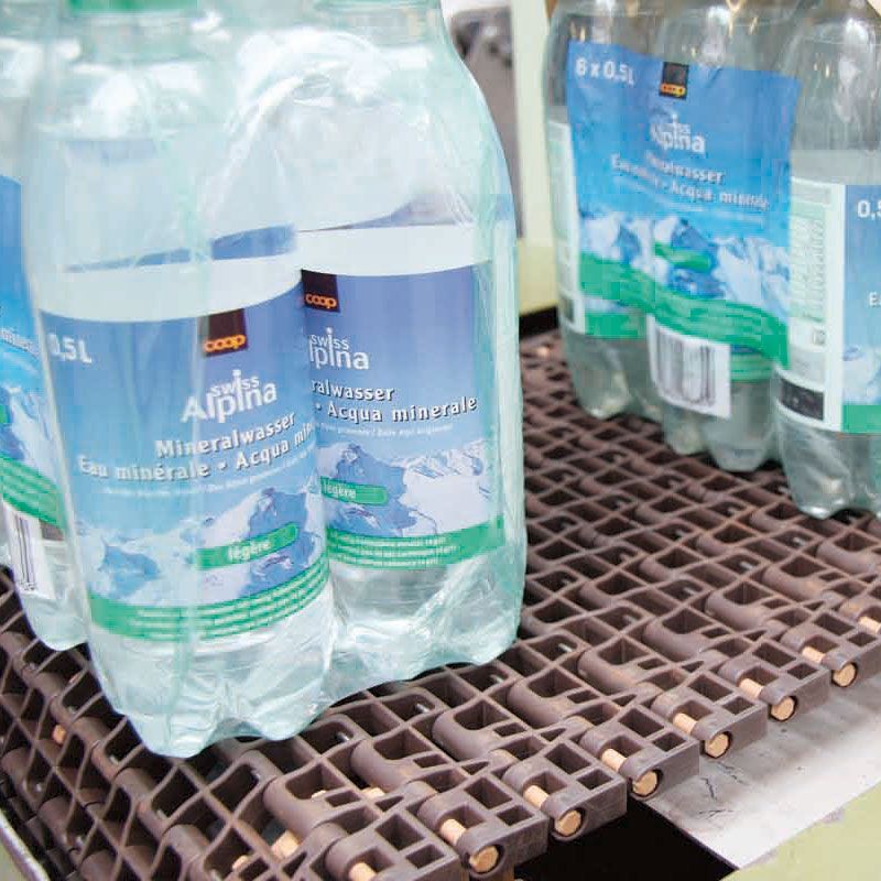 Las botellas de agua mineral Alpina están en una cinta transportadora.