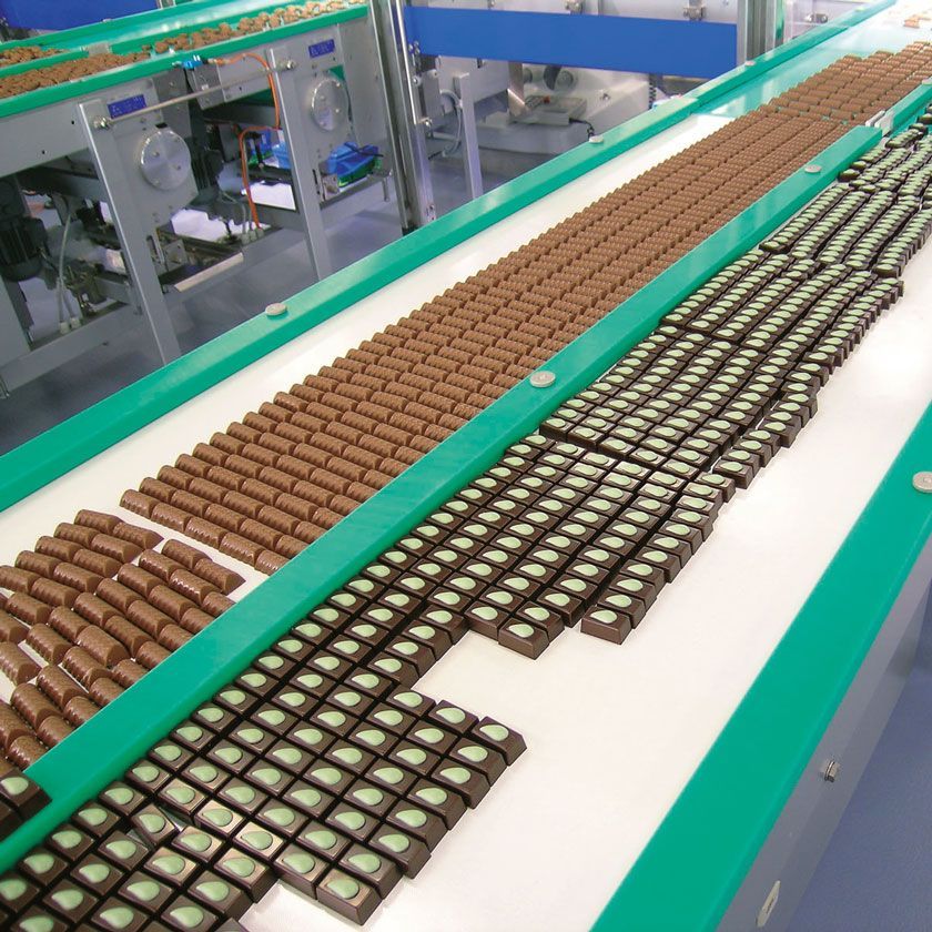 Una cinta transportadora con muchas barras de chocolate encima
