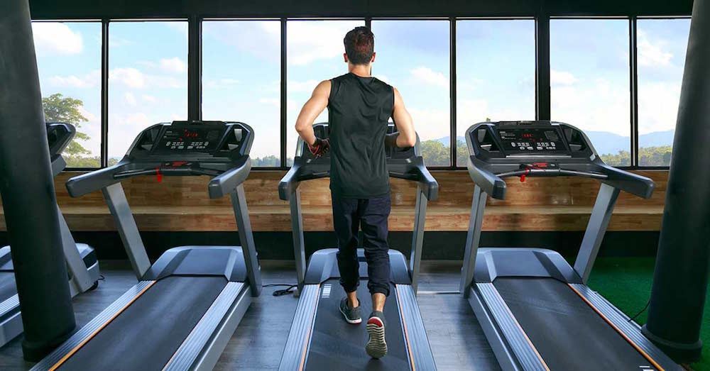 Un hombre está corriendo en una cinta de correr en un gimnasio.
