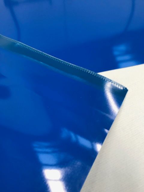 Un primer plano de un trozo de plástico azul sobre una superficie blanca.