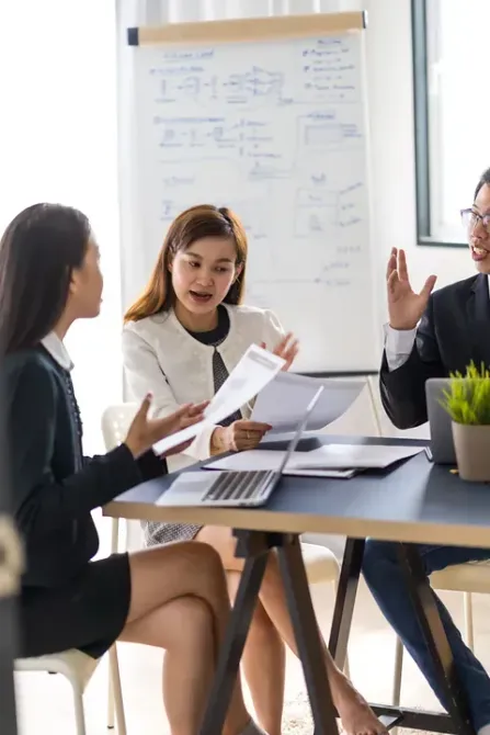 Un grupo de personas están sentadas alrededor de una mesa teniendo una reunión.