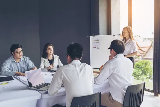 Un grupo de personas están sentadas alrededor de una mesa teniendo una reunión.