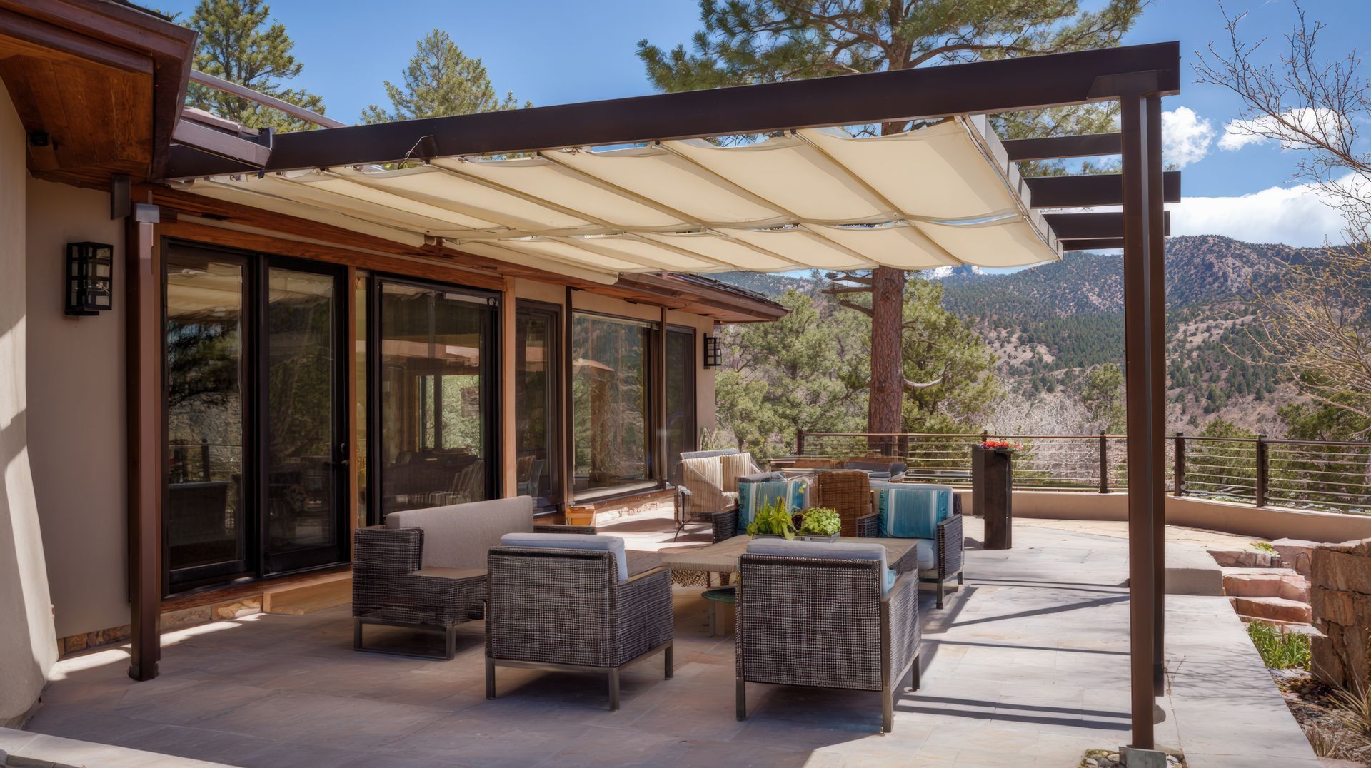 Patio couvert avec sièges en osier et vue sur les montagnes désertiques à côté d'une maison moderne.