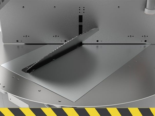 Machine industrielle en métal avec une goulotte inclinée noire au-dessus d'une plateforme argentée et des panneaux rivetés
