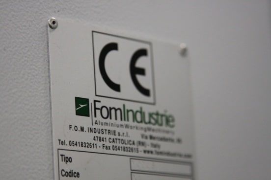Gros plan sur une étiquette de certification CE apposée sur un panneau métallique gris portant la marque FomIndustrie.