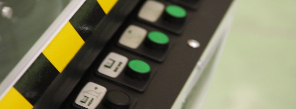 Gros plan sur un panneau de commande noir avec des boutons rétroéclairés en vert et des touches blanches à côté d'une bande jaune