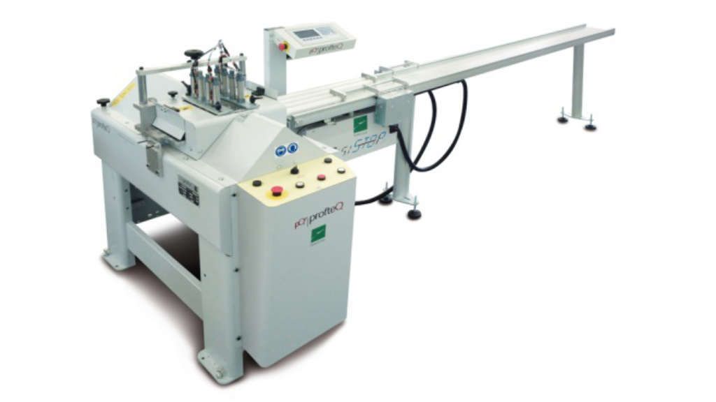 Machine de découpe industrielle automatique avec une longue table d'alimentation et un panneau de commande, présentée sur fond blanc.