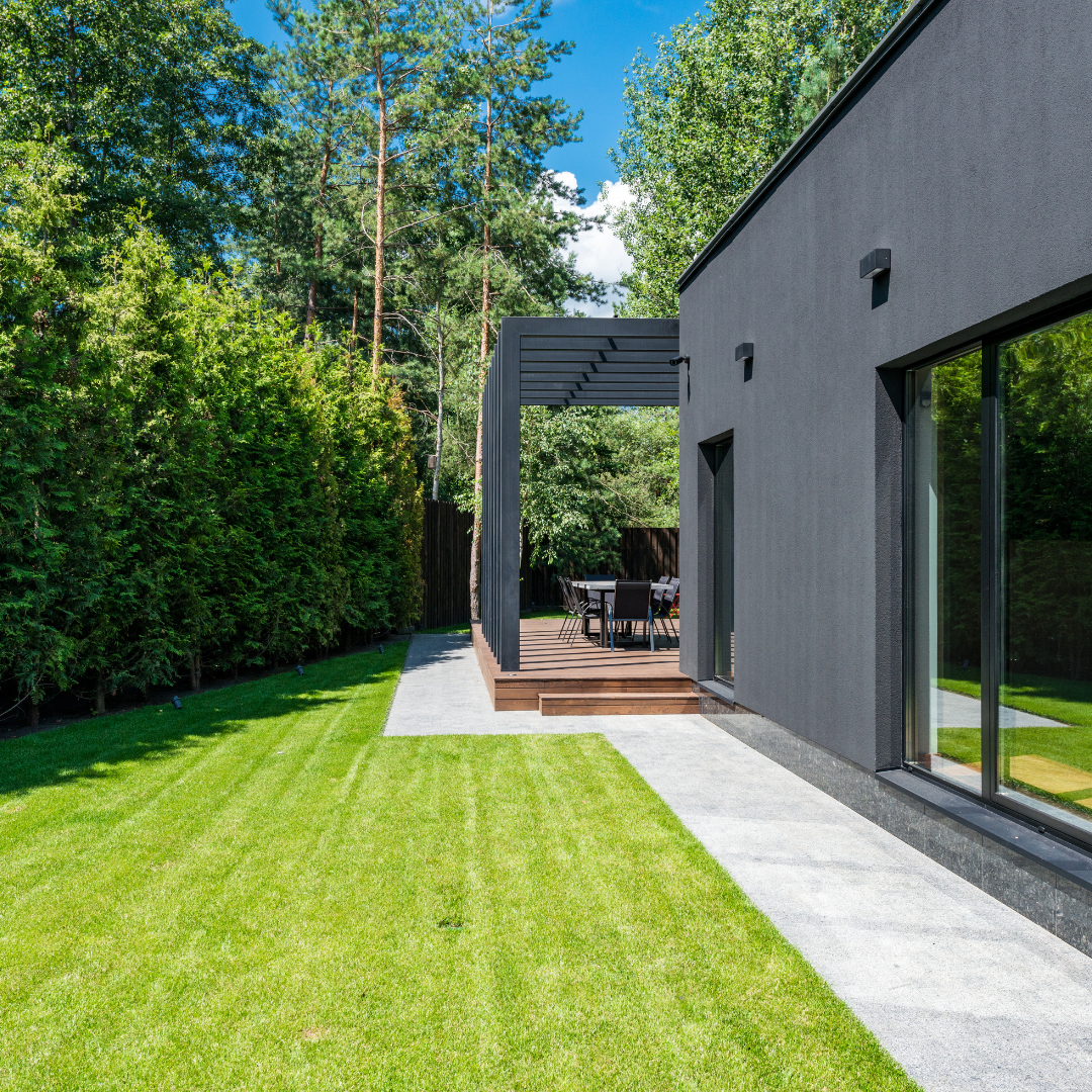 A black house with a large lawn in front of it.