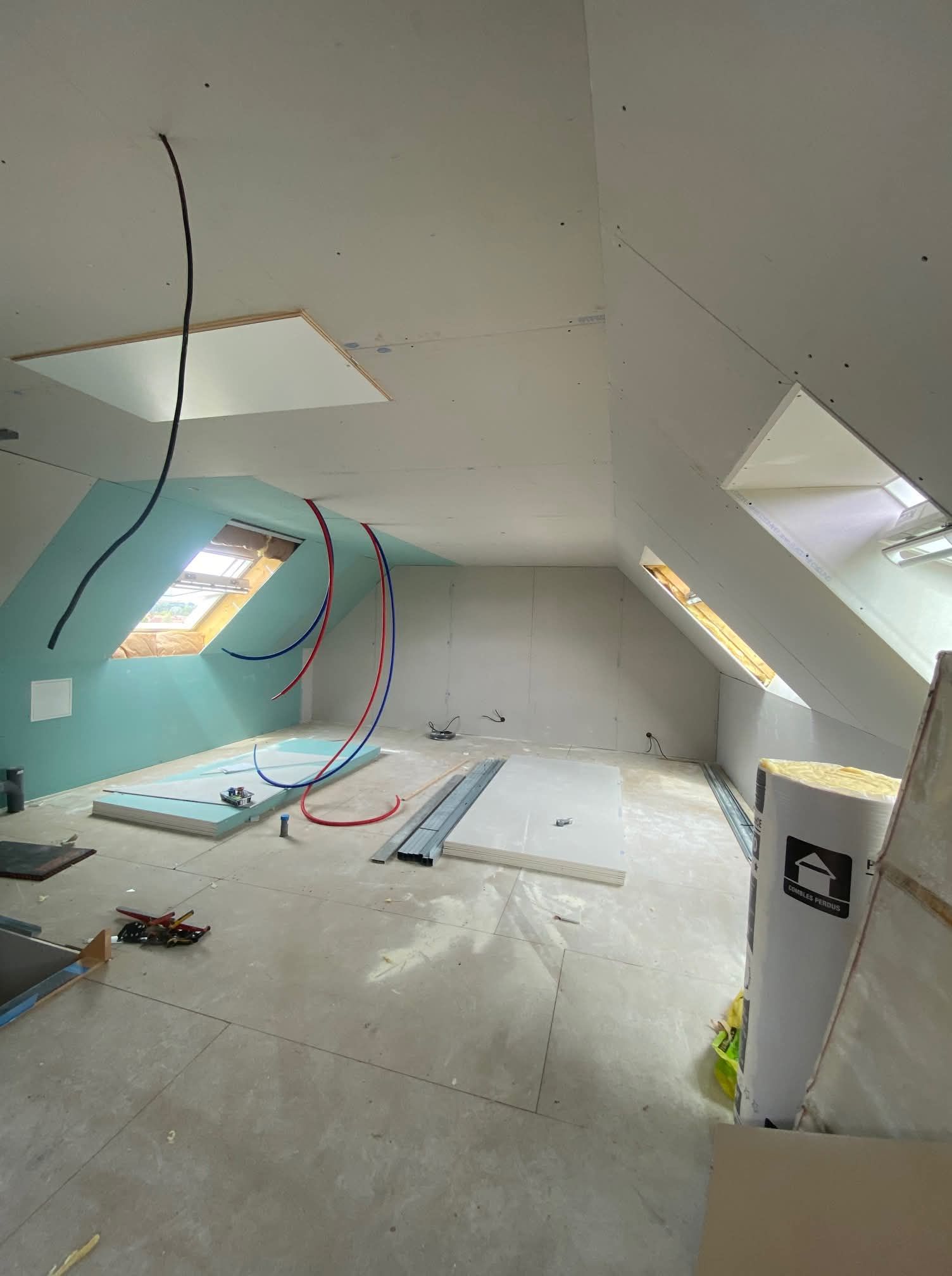 Intérieur d'un grenier en construction ; câbles et tuyaux apparents et cloisons