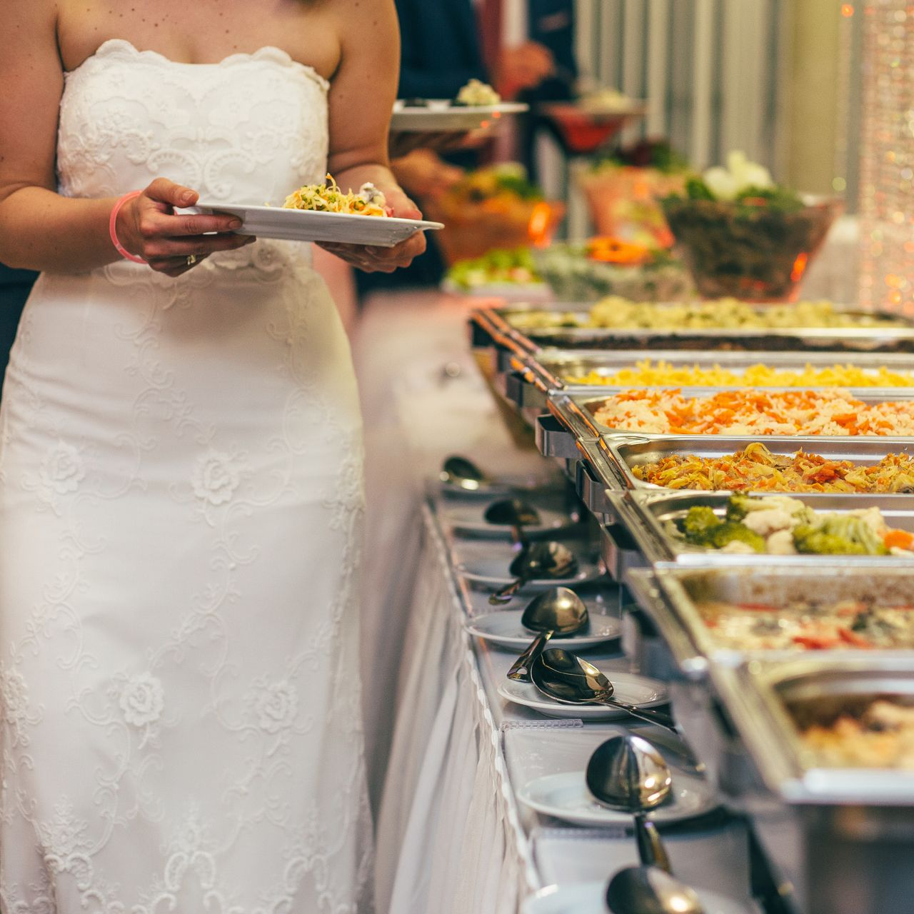 Une mariée à côté d'un buffet.