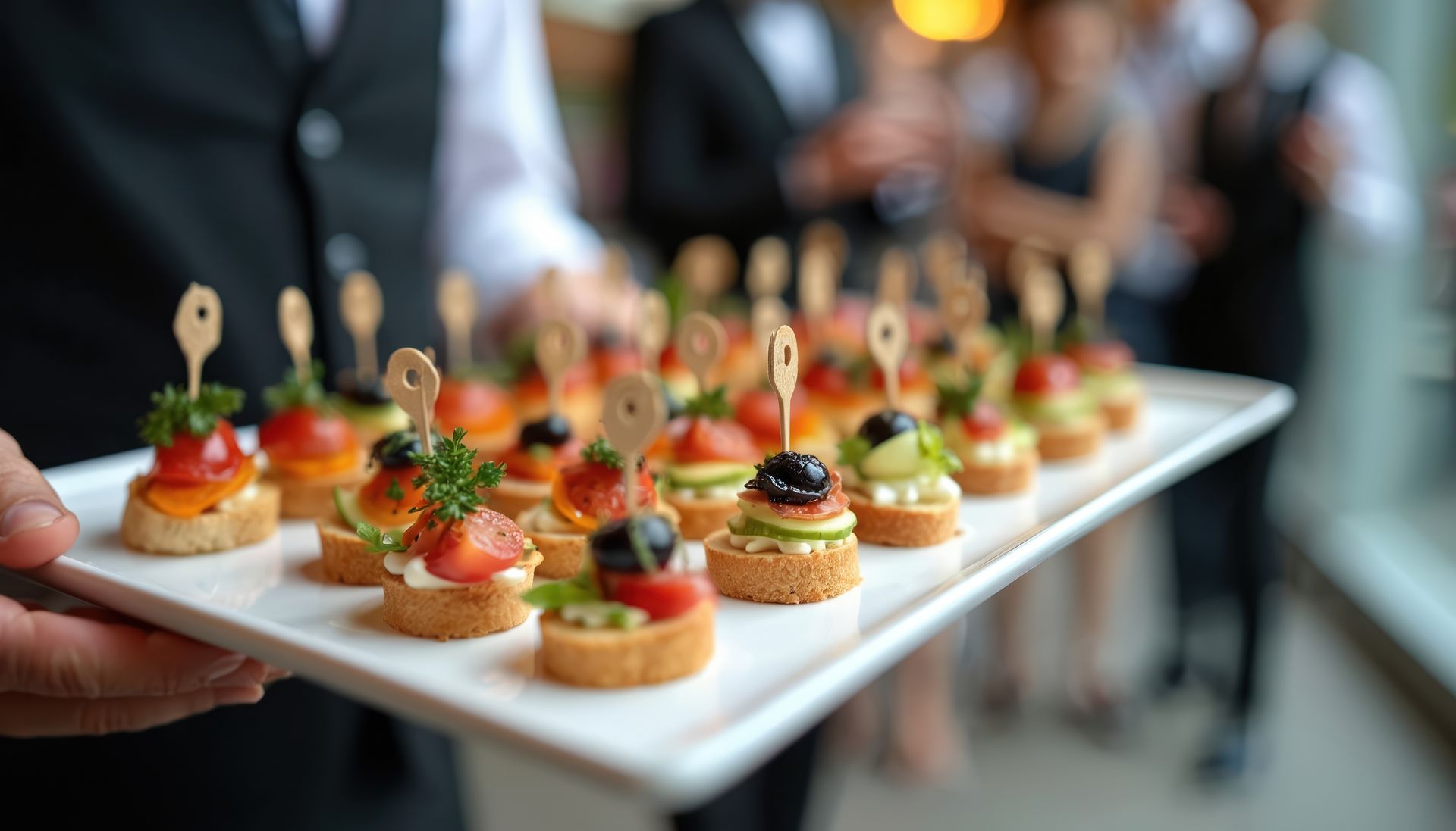 Des bouchées aux olives sur un plateau blanc.