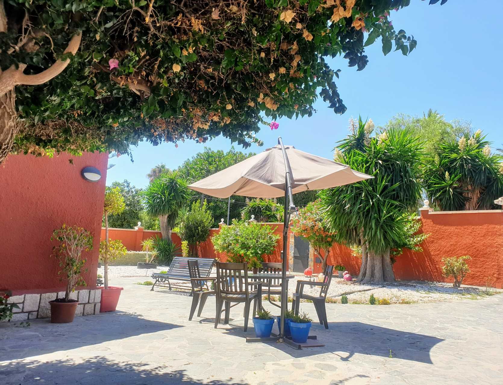 Un patio con una mesa y sillas bajo una sombrilla.