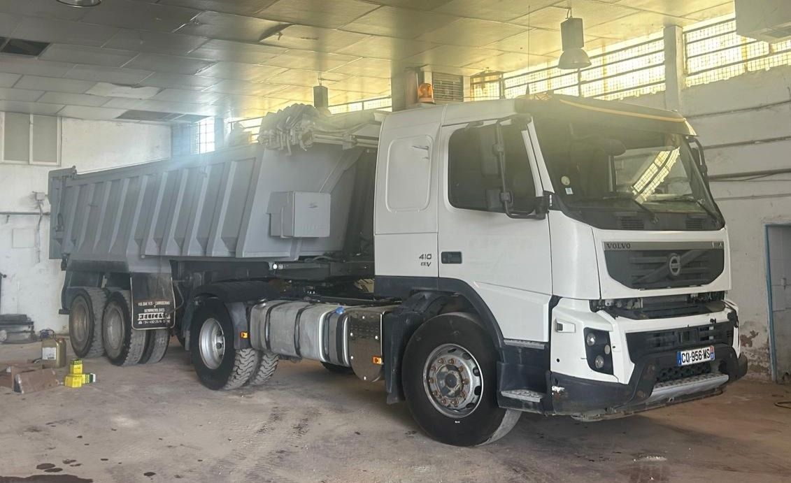 Camión volquete blanco estacionado en un almacén, listo para trabajar.