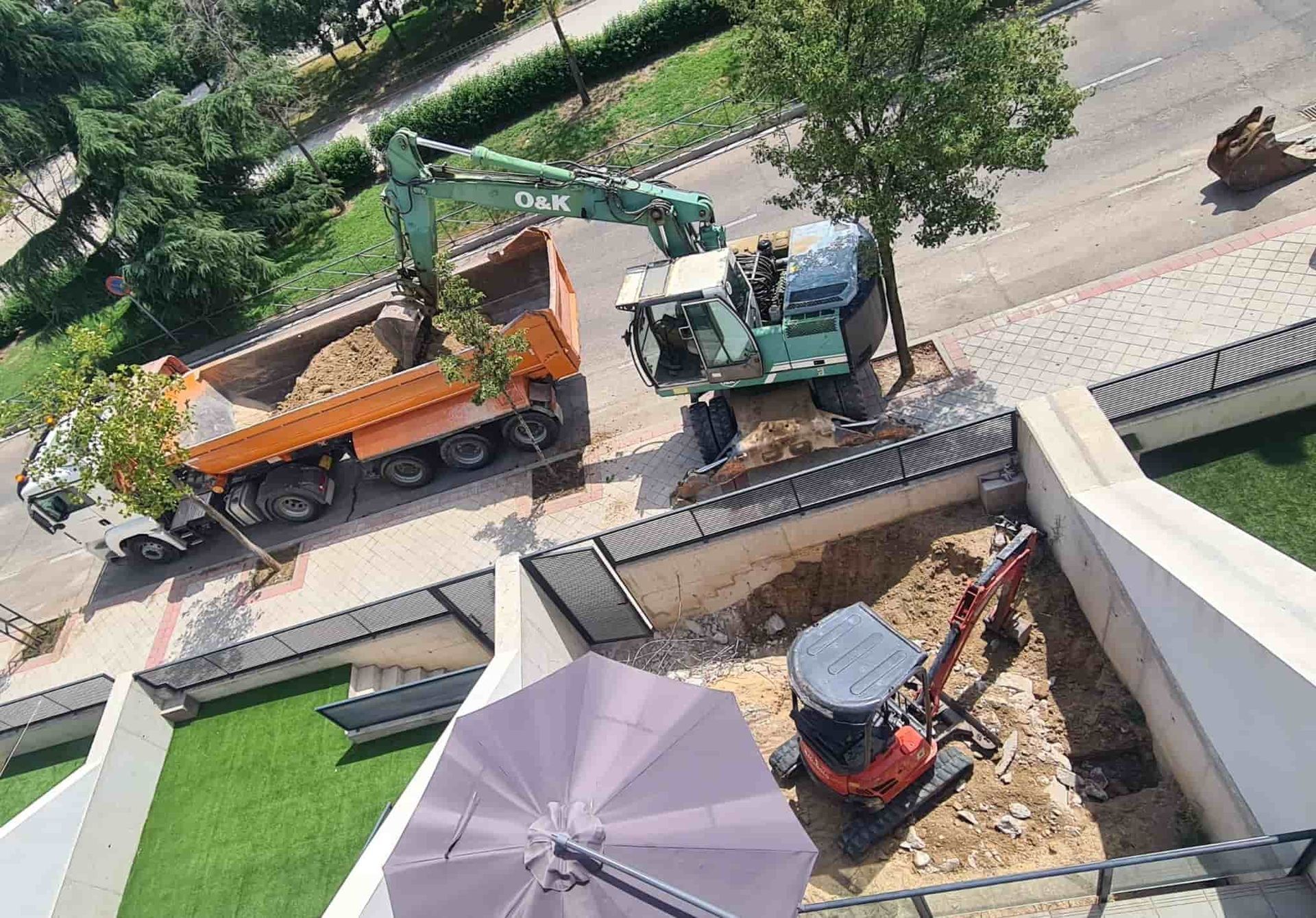 Obra con una excavadora cargando tierra en un camión volquete naranja. Miniexcavadora en una zanja.