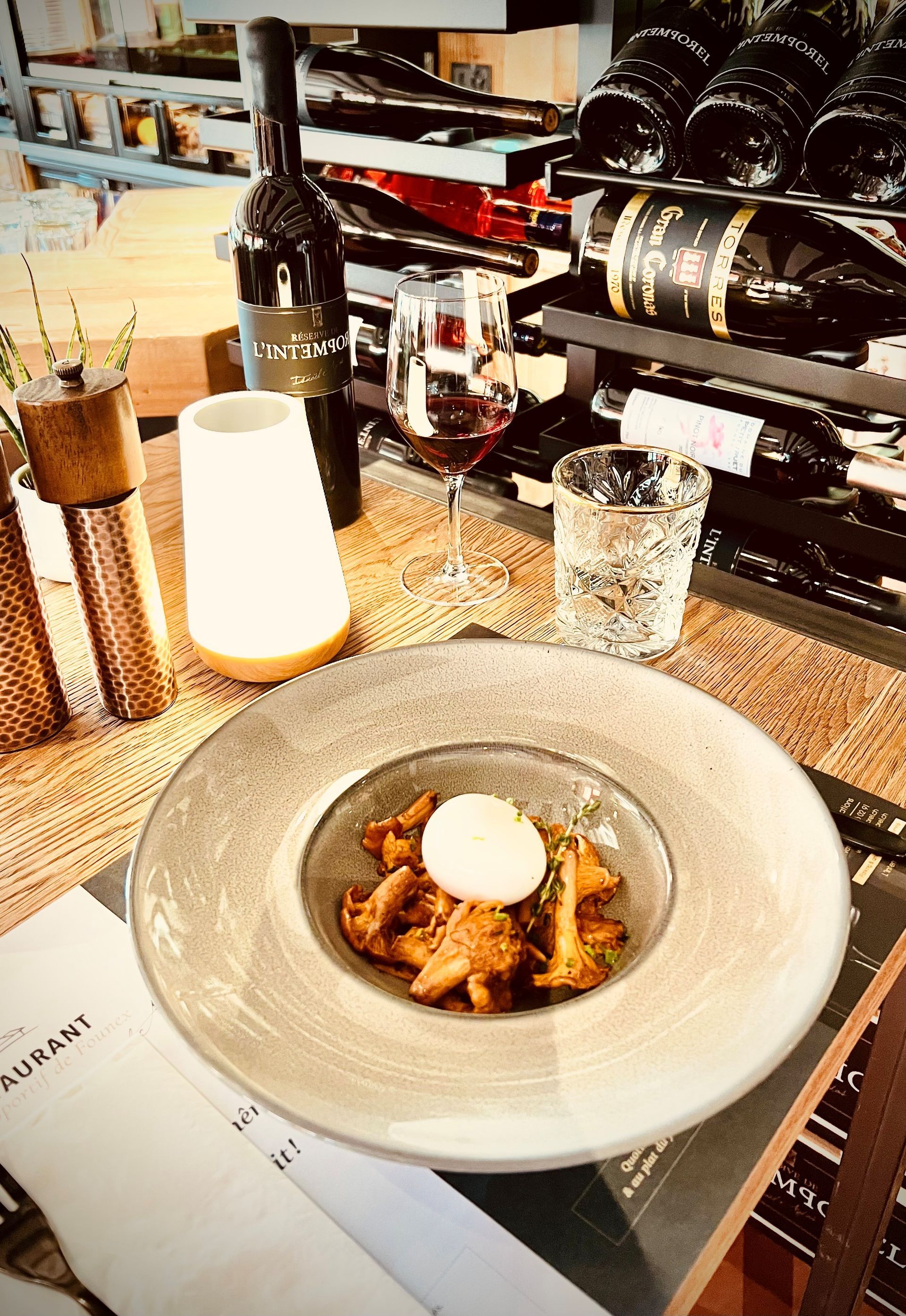 Dessert présenté sur le comptoir d'un restaurant, à côté de bouteilles de vin et de verres.