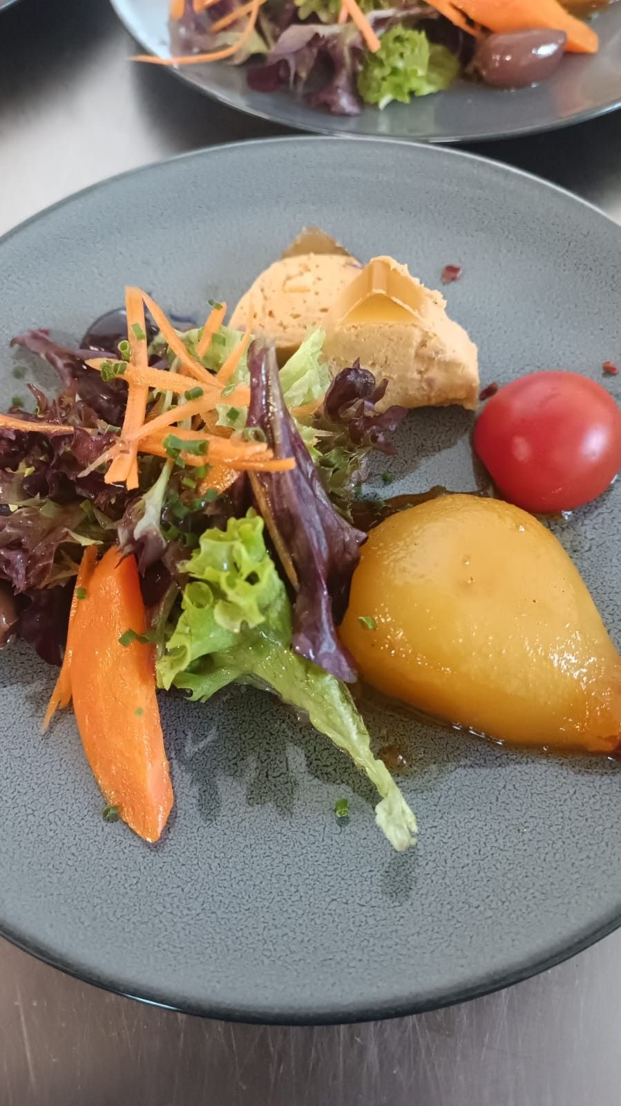 Salade composée raffinée avec légumes rôtis, tomate cerise et poire, présentée dans un bol gris.