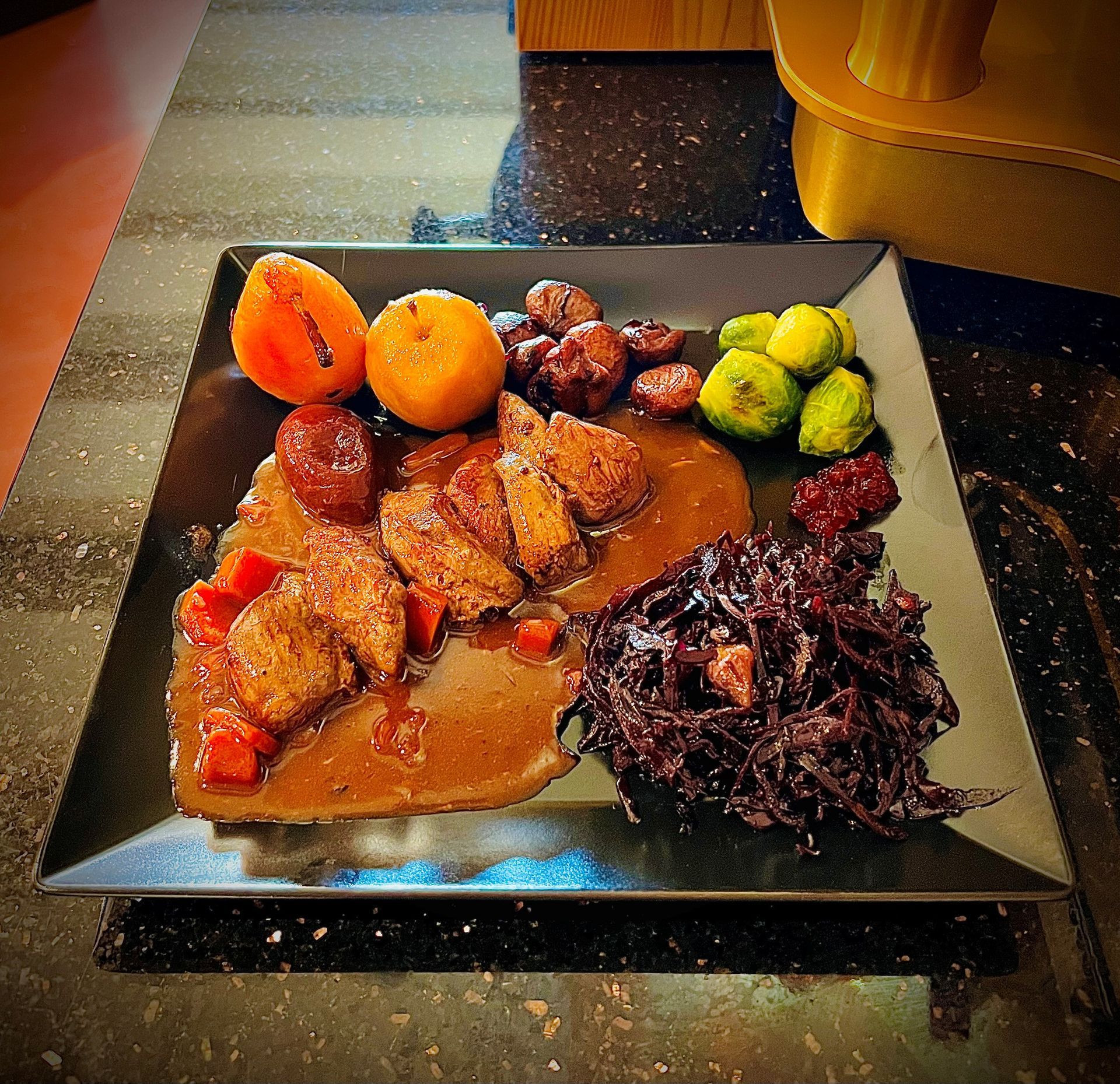 Assortiment de desserts présentés sur une table noire, comprenant un gâteau à l'orange, des pâtisseries et des garnitures de fruits.
