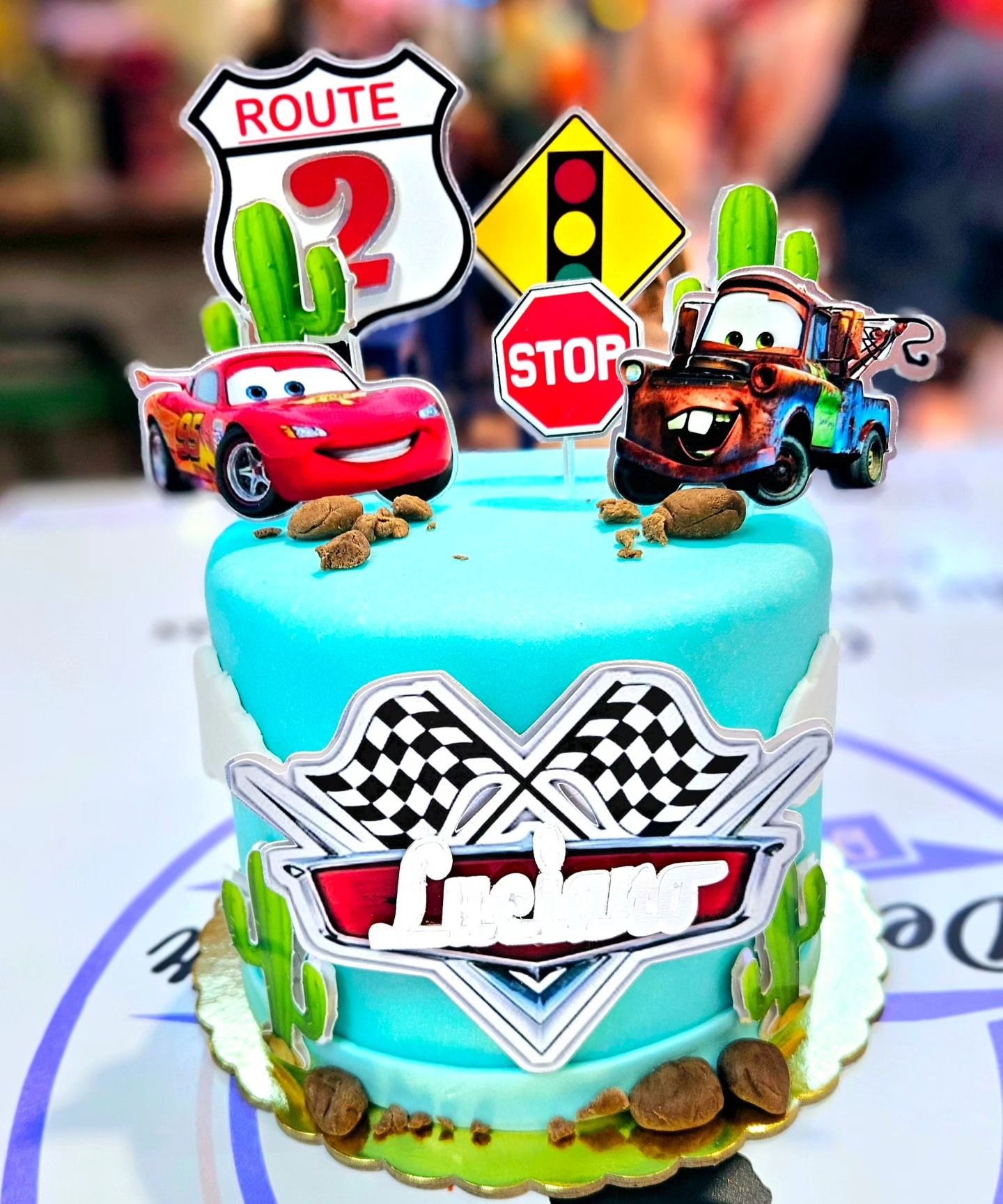 Un pastel con coches encima está sobre una mesa.