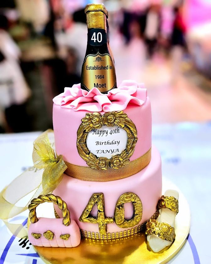Un pastel rosa y dorado con una botella de champán encima.