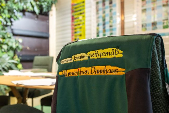 Vor einem Tisch steht ein Stuhl mit einem grünen Hemd darauf.