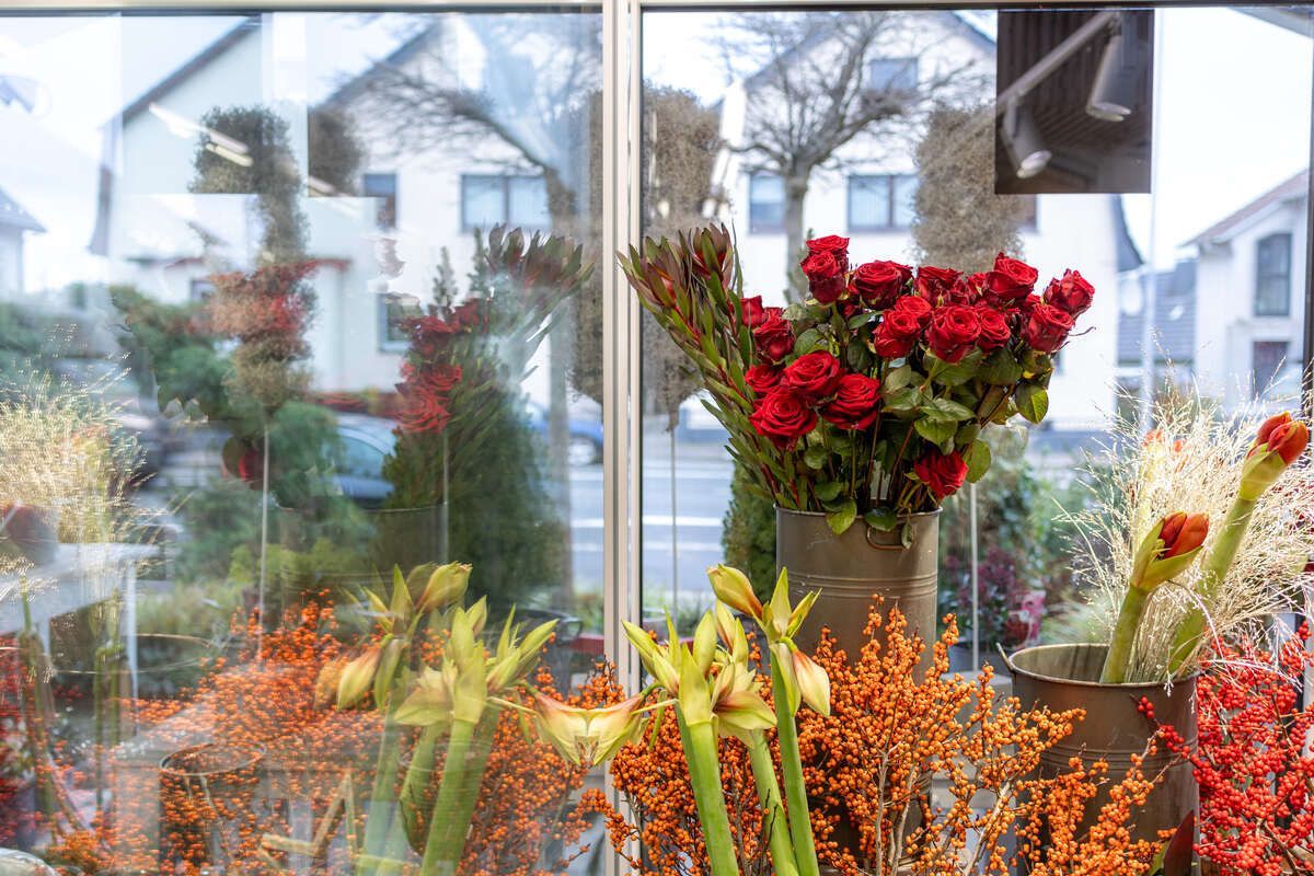 Ein Strauß Blumen steht vor einem Fenster.
