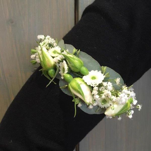 Ein Armband mit weißen Blüten und grünen Blättern am Handgelenk einer Person