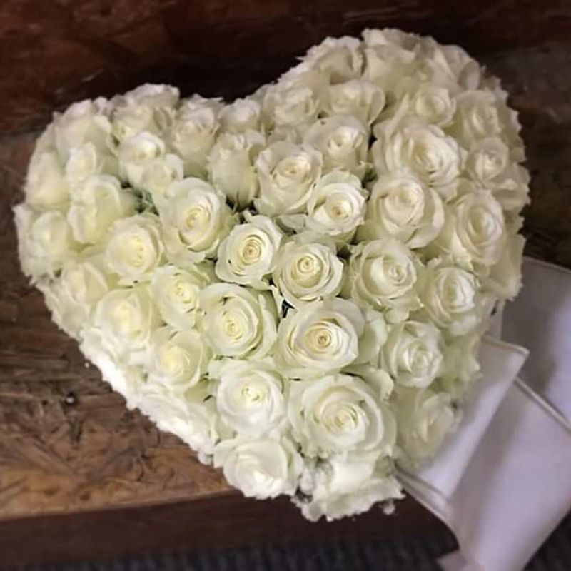 Auf einem Tisch liegt ein Herz aus weißen Rosen.