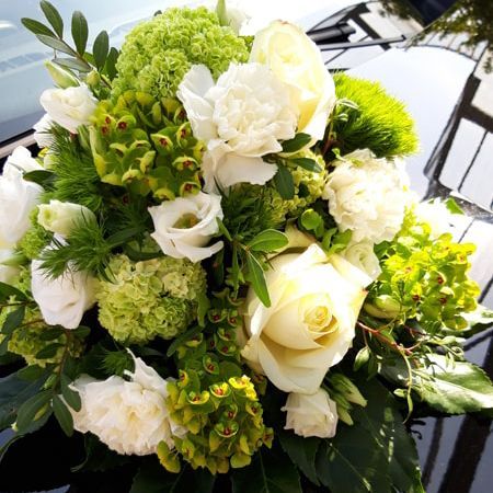 Ein Strauß weißer und grüner Blumen auf der Motorhaube eines Autos