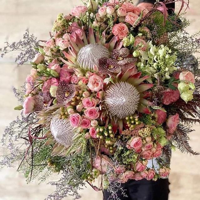 Eine Person hält einen großen Strauß rosa Blumen.