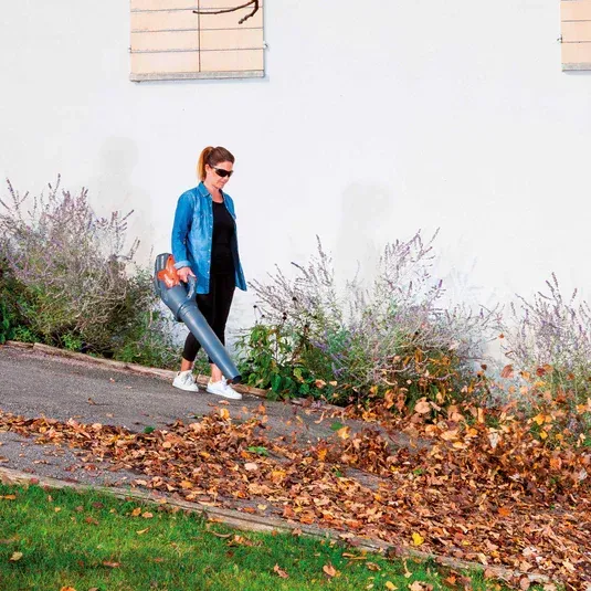 Une femme passe la souffleuse sur des feuilles