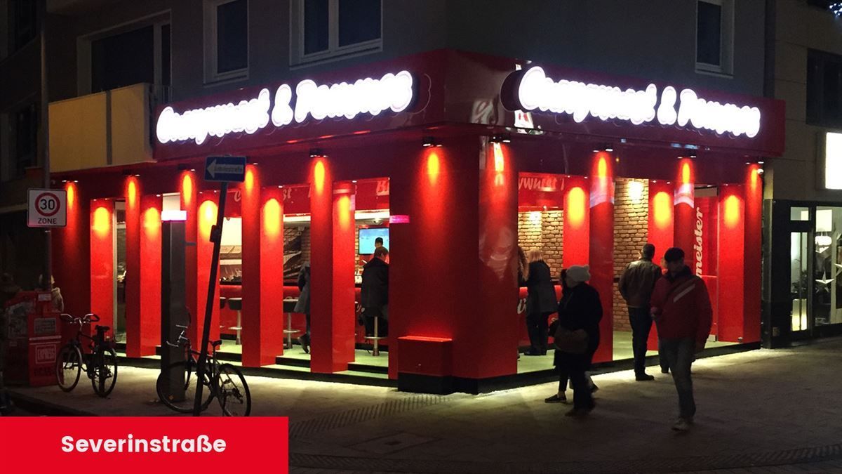 Eine Gruppe von Menschen steht vor einer Pizzeria