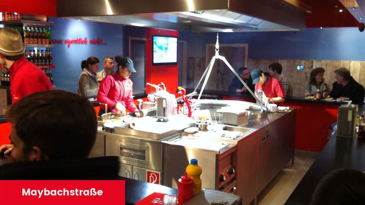 Eine Gruppe von Menschen sitzt an Tischen in einem Restaurant mit den Worten „maybuchatrabe“ auf der Unterseite