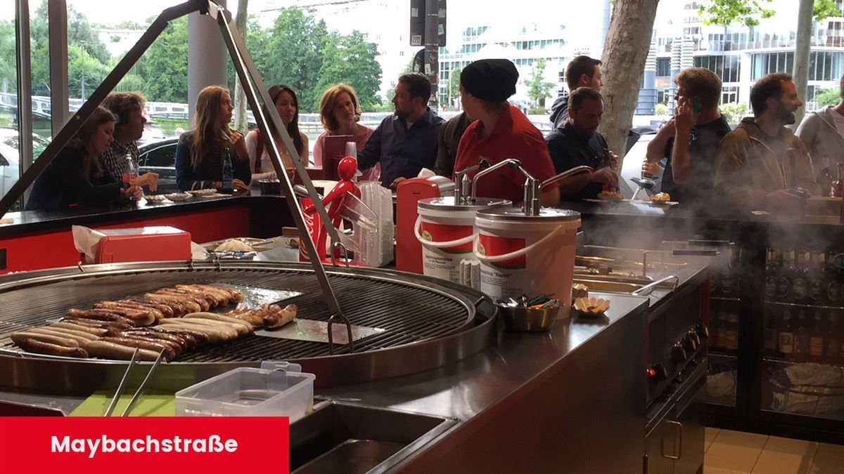 Eine Gruppe von Menschen sitzt an Tischen in einem Restaurant mit einem Schild mit der Aufschrift „maybuchatrabe“