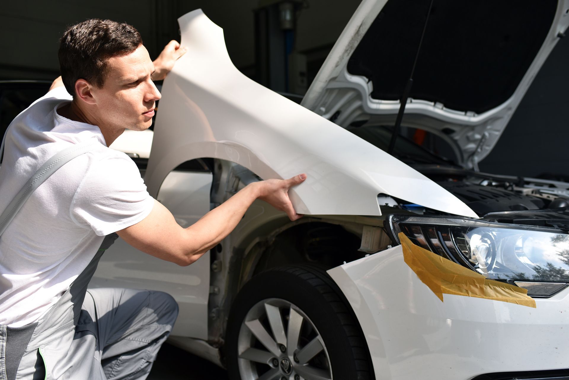 Un mécanicien qui rempace un élément de carrosserie