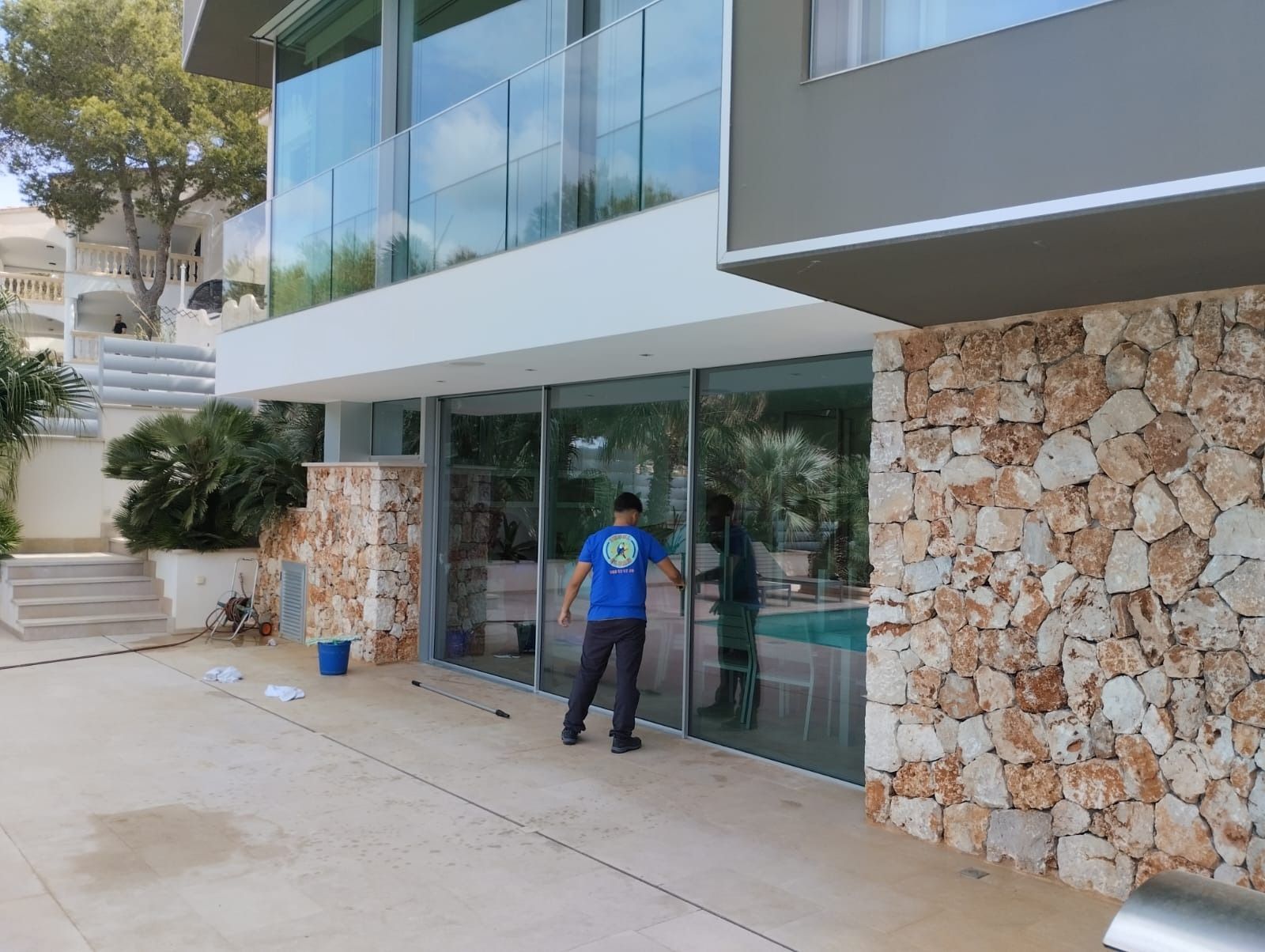Un hombre con una camisa azul está limpiando las ventanas de un edificio grande.