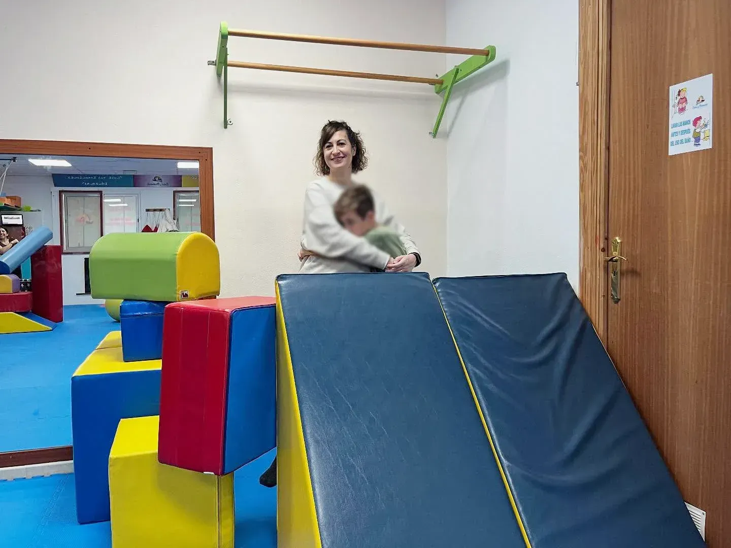 Una mujer está colocando a un niño sobre una pelota de ejercicio amarilla.